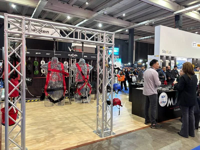 Arneses de seguridad rojos y cascos exhibidos en el stand de Macaya Safety