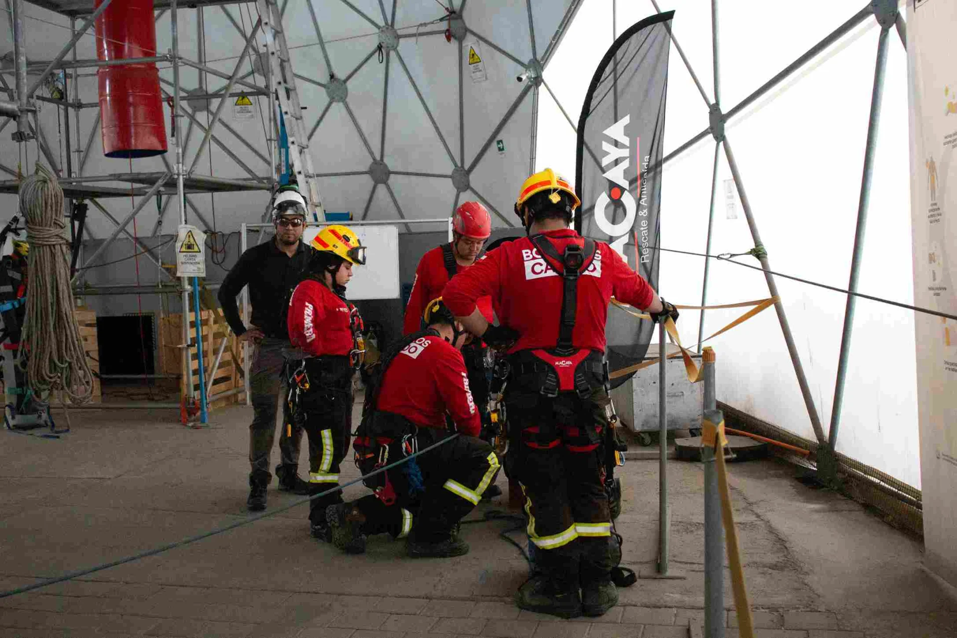 Instructor supervisando a alumnos con arneses Macaya y cascos durante una práctica de capacitación en altura en el domo de Macaya Safety